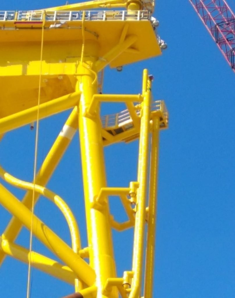 Close-up view of a yellow offshore jacket structure with ladders and platforms.