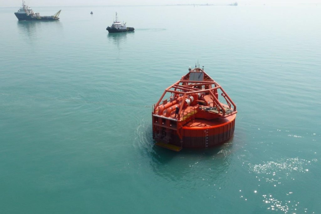 Red offshore buoy floating in calm water.