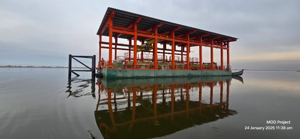 Red offshore platform frame with reflections on water, early morning.