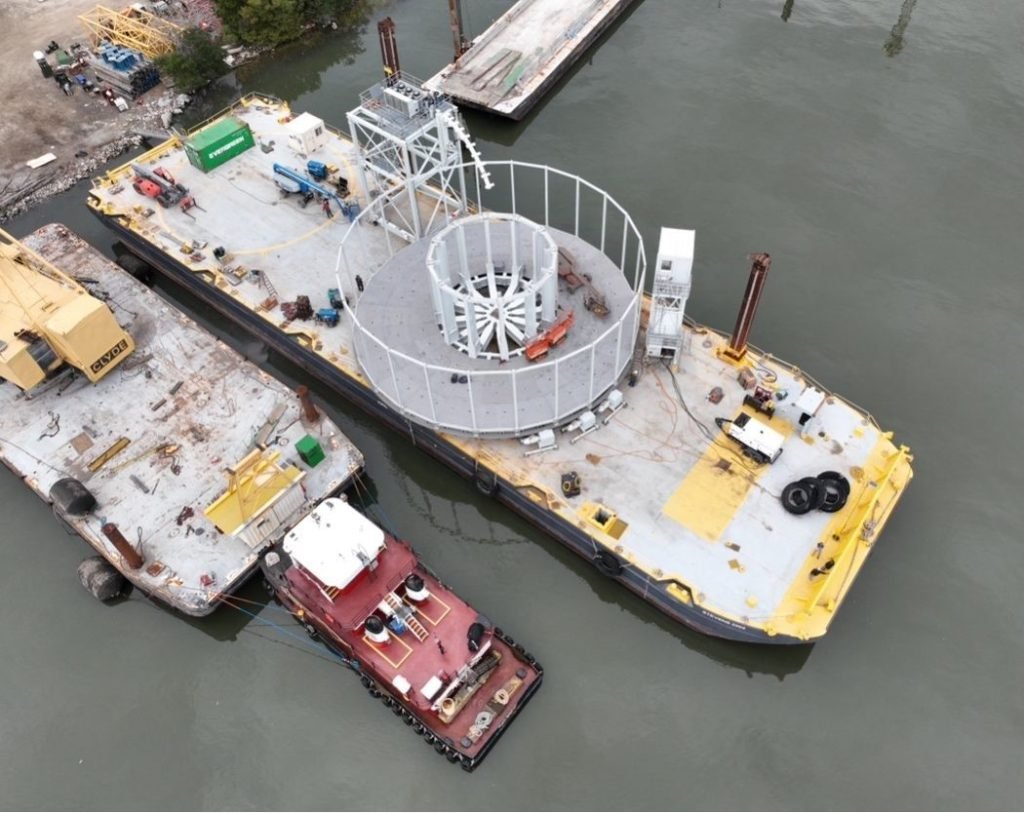 Top-down view of large carousel on barge near port.